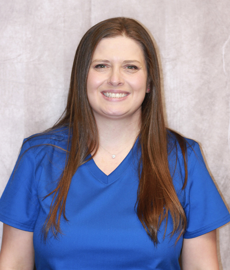 Joy, smiling, in blue scrubs