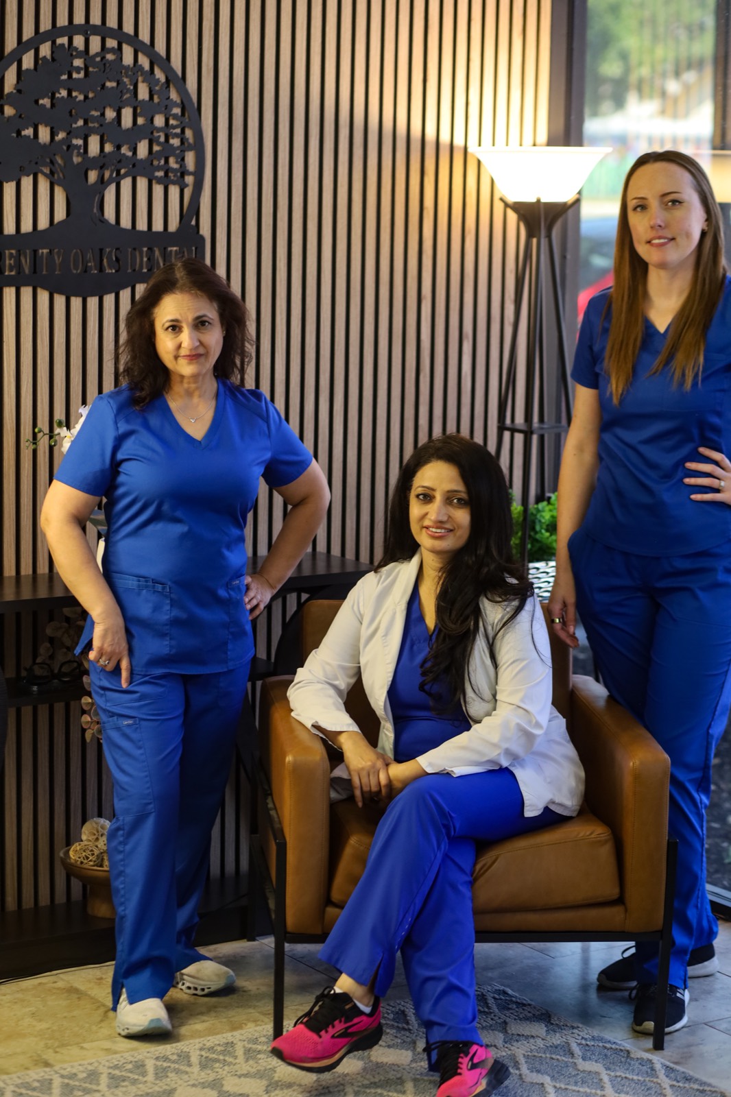 Dr. Bhatti and the Serenity Oaks Dental team in the office lobby, in front of the oak tree logo