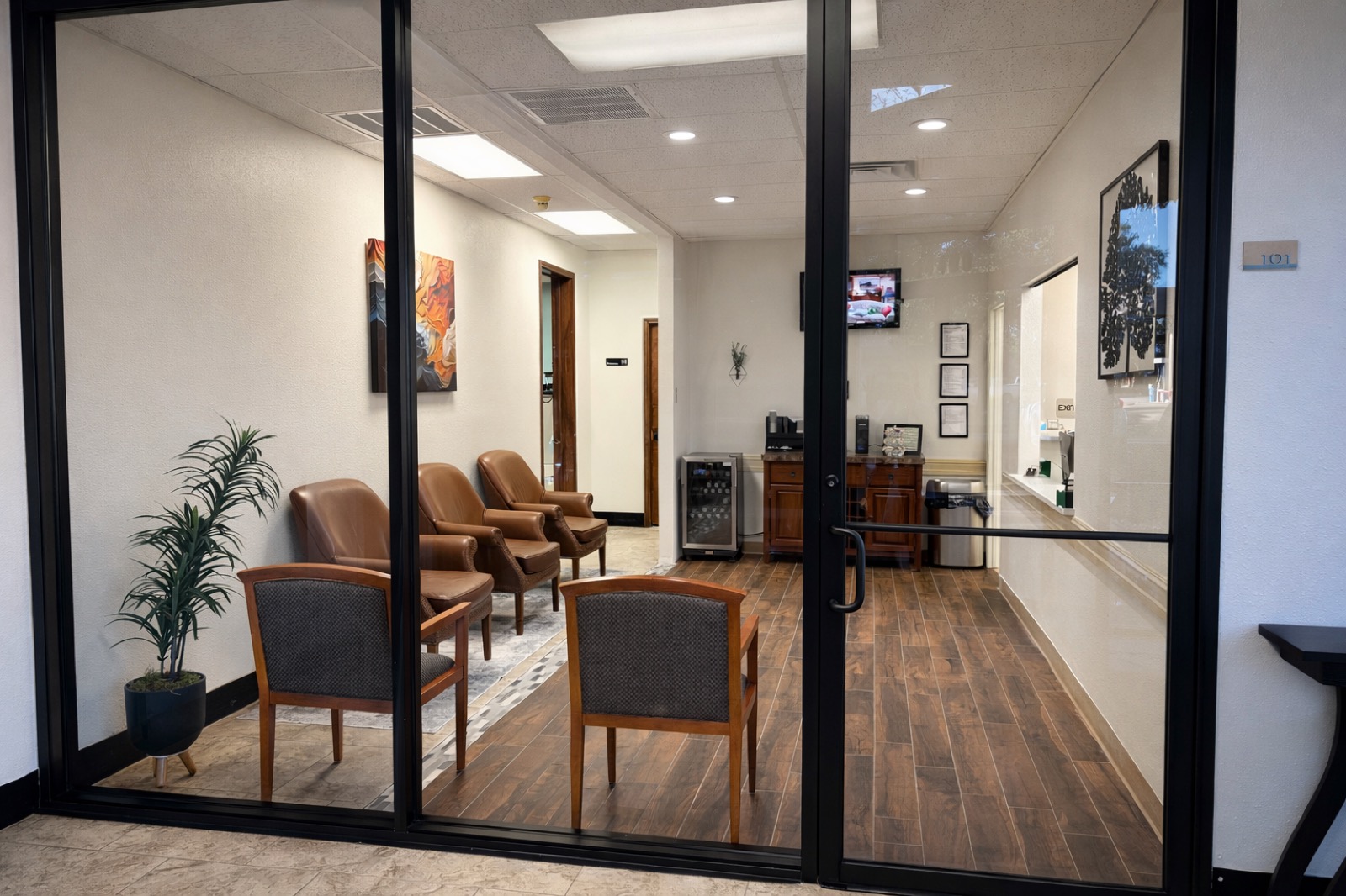 The waiting room seen through glass doors, with chairs and a beverage station